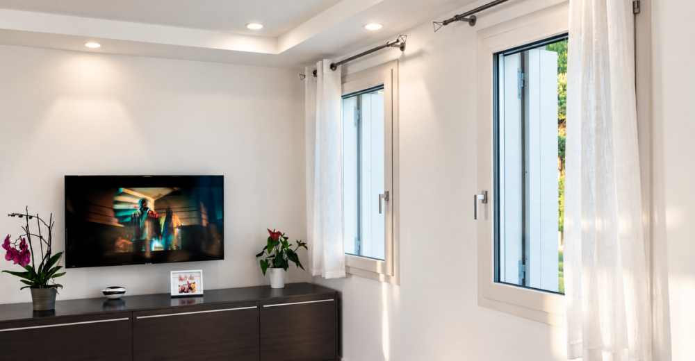 Soggiorno con finestre in PVC Veka bianche e tende leggere