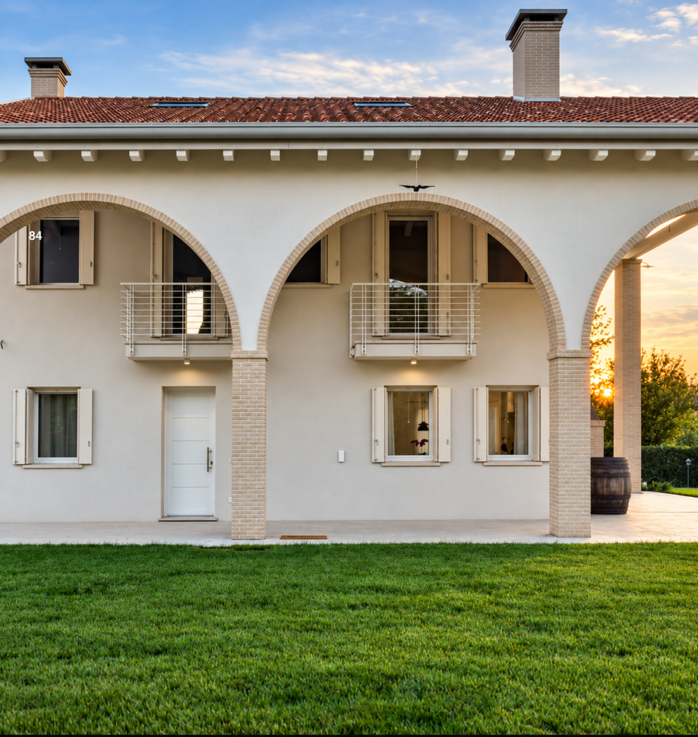 Facciata con archi e finestre in PVC con scuri, Casa G.M.