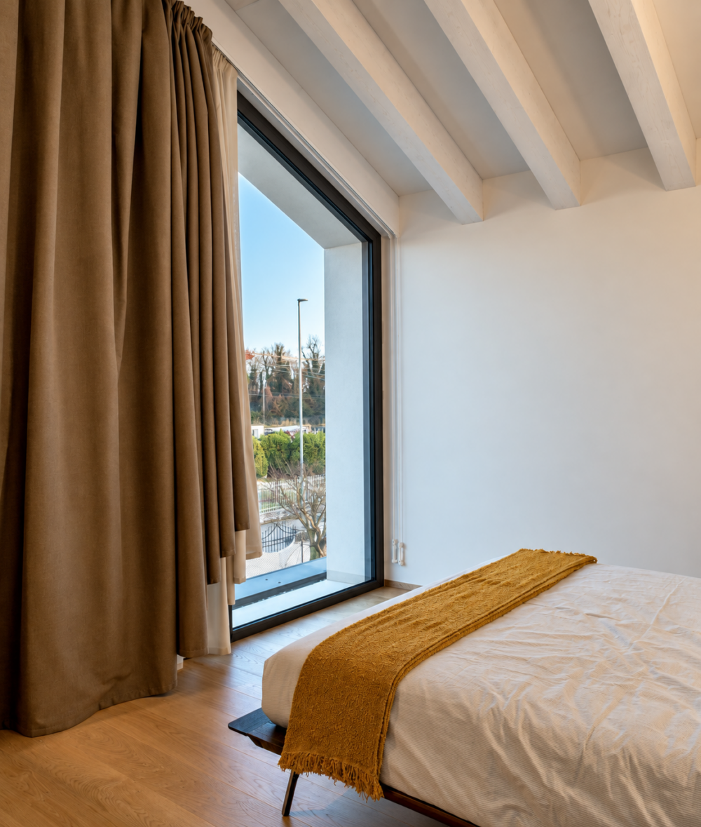 Camera da letto con travi a vista e finestra a tutta altezza