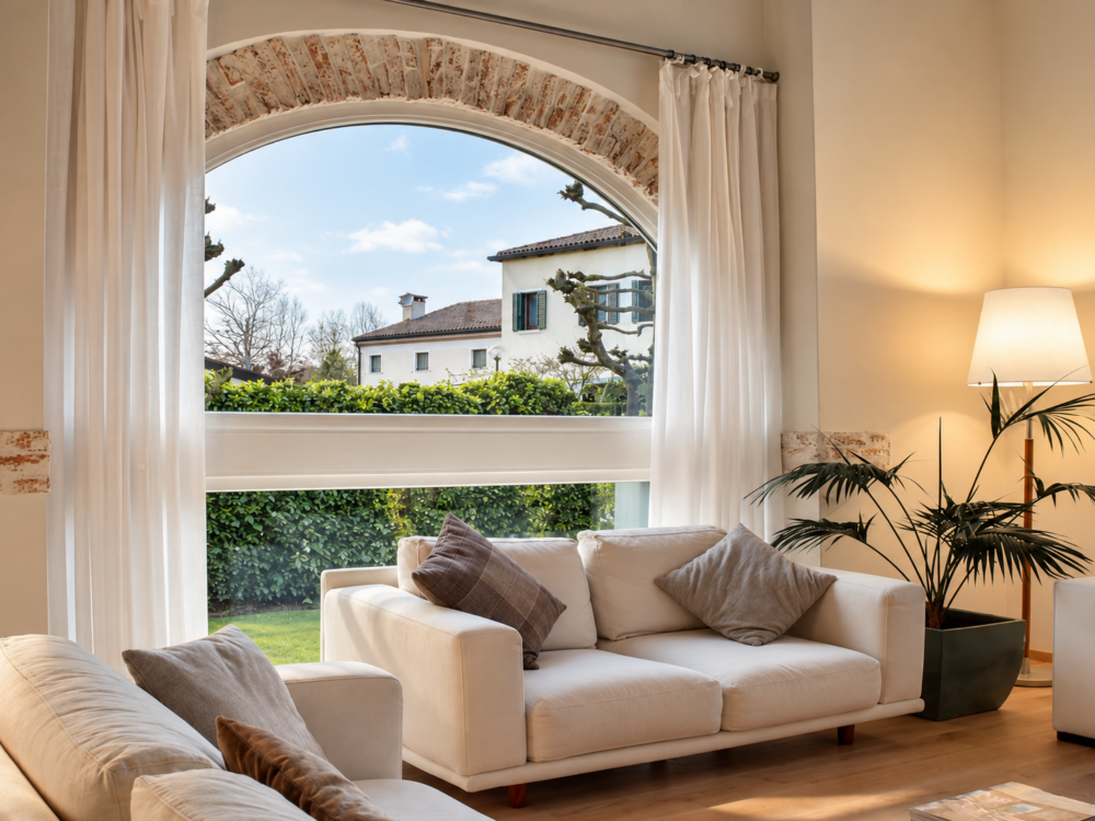 Soggiorno con finestra ad arco e vista sul giardino